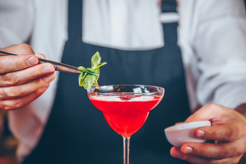 Barman decorating cocktail at a nightclub. Nightlife and entertainment concept. Horizontal, cold toning