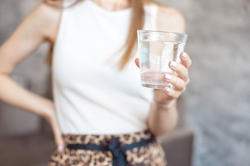 Close-up woman with slim body holding a glass of water, rear veaw