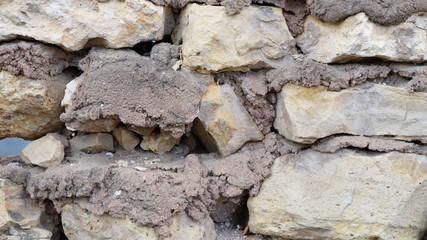 wall made of roughly treated natural stone with cement mortar
