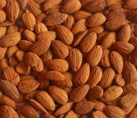 Background pattern, raw peeled almonds situated chaotically. Top view.