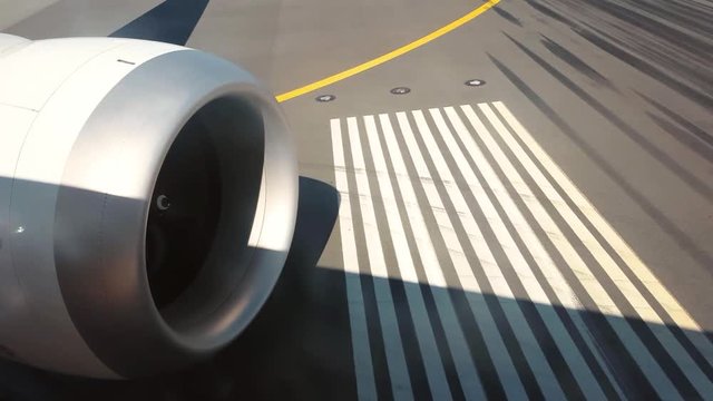 View from Airplane of Jet Engine spinning as Plane taxis on runway