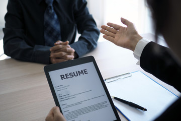 Executives are interviewing candidates and holding a tablet, opening the resume from the email that...