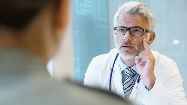 Mature doctor talking to patient in modern clinic