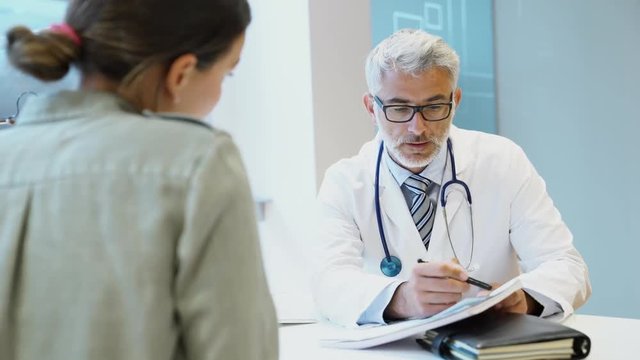 Mature doctor talking to patient in modern clinic