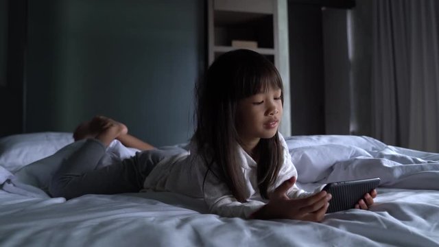 5 years old Asian girl Using smartphone , watching cartoon, playing games in bedroom happily