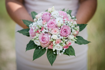Braut hält und zeigt ihren Brautstrauß mit rosa Rosen zur Kamera
