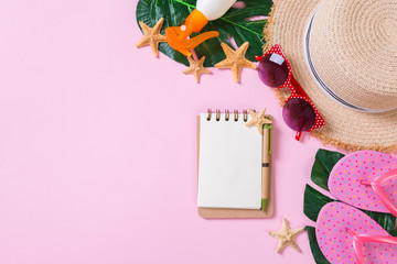 Beach accessories with straw hat, sunscreen bottle and seastar on pink background top view with...