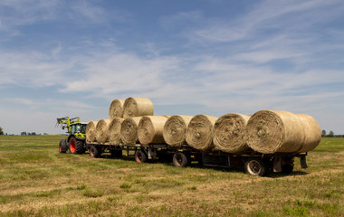 tractor pulling a long trailer with a load of hay bales