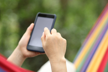 Relaxing in hammock with smartphone in forest