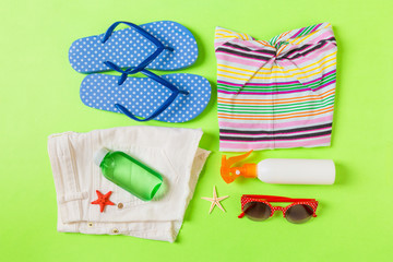 Flat lay composition with Beach accessories on green color background. Summer holiday background. Vacation and travel items top view
