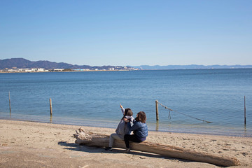 浜辺の流木に座る2人