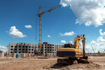 Excavator at a construction site against the background of a tower crane. Construction, technology