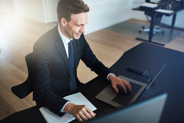 Smiling businessman working on a laptop at his office desk