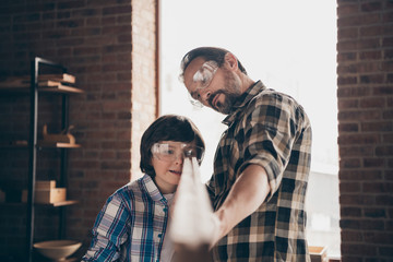 Fototapeta premium Close up photo of nice attractive nice focused charming daddy kid brunettes beard look occupation profession hobby analyze glasses goggles protective checkered shirt outfit indoors interior industrial