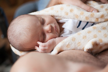 Young father holding his sweet adorable slepping newborn child
