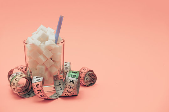 Glass Full Of Cubes Sugar With Straw On A Beautiful Peach  Background  - Unhealthy Diet Concept.