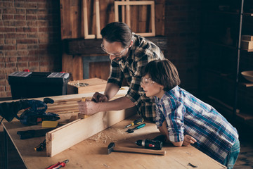 Profile side view photo of nice charming kid spend time daddy builder build watch cart workstation...
