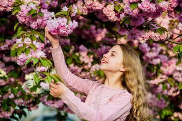 Fototapeta premium Girl cherry flower background. Happy spring vacation. Park and garden. Girl little child in spring flower bloom. Enjoy smell of tender bloom sunny day. Sakura flower concept. Gorgeous flower beauty