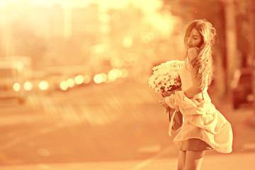 happy girl with flowers in the city / summer photo young beautiful girl holding a bouquet of flowers on a city street