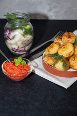 In the background is a jar of celery and red onions, in a bowl there is red caviar and young potatoes, fried in butter. 