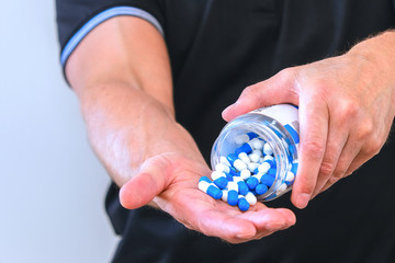The man poured a handful of sports capsules into his palm. Reception before training. Increase...