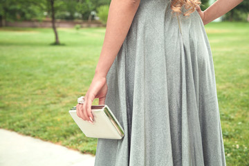 Woman in shining silver dress walking in the park.