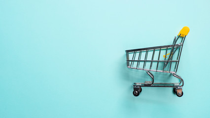 Shopping cart on blue background. Top view or flat lay. Shop trolley at supermarket as sale,...