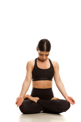 Young woman siting in lotus yoga position and yoga breathing on white background 