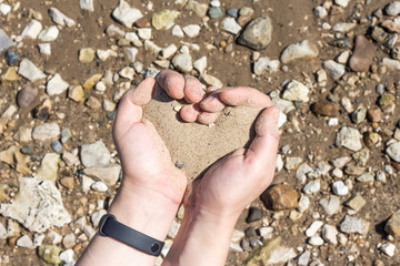 hands holding a sand in the palms of heart,the concept of life running out like sand through fingers