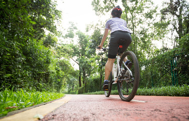 Woman cyclist riding a bike on sunny park trail in summer