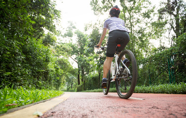 Woman cyclist riding a bike on sunny park trail in summer