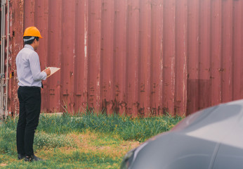 Male engineer inspection checking on container background With note on notepad or...