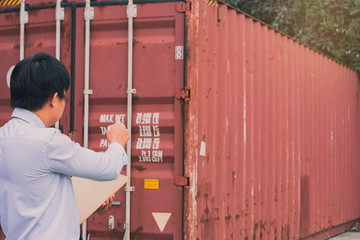 Male engineer inspection checking on container background With note on notepad or...