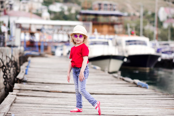 Stylish baby girl 3-4 year old wearing summer clothes outdoors. Looking at camera. Childhood.