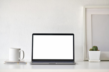 Blank white screen laptop with office supplies on white desk workspace.