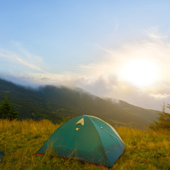 green touristic tent im a mountain at the sunset, hiking evening scene