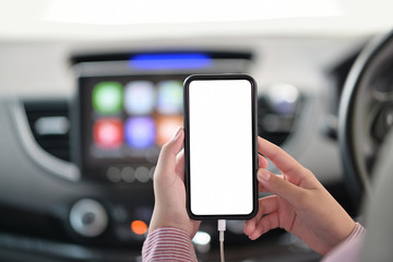 Cropped shot of female hand holding mobile phone in car.