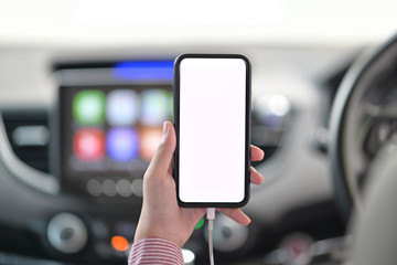 Cropped shot of female hand holding mobile phone in car.