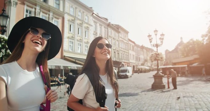 Beautiful smiling female tourists enjoying trip, smiling and looking around on warm summer day