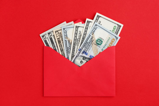 Fan US dollars in cash in red envelope on red background. Money mail concept. Flat lay, minimal style.