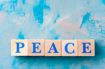 Wooden cubes with word PEACE on blue table.