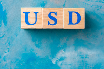 Wooden cubes with word USD on blue table.