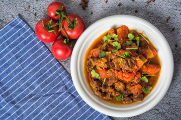 Soup with beef tomatoes and fresh vegetables. On a wooden background. Top view. Copy space.