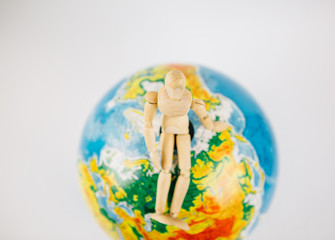 Wood puppet with globe.Wood mannequin sitting on top of a world globe to protect isolated on white  background.