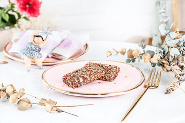Veggie healthy Bars with Figs served on rose plate above white background. Close up horizontal food photo. Gluten free, healthy dessert. Vegan food and sweets. Homemade snack. Copy space