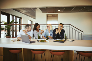 Obraz premium Laughing coworkers having pizza and beer after work