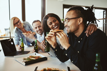 Diverse group of laughing office colleagues having pizza and beers