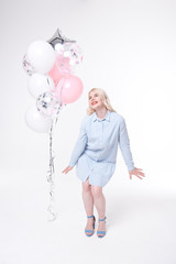 Full length portrait of a joyful young woman, rejoices and celebrates on a white background with multi-colored balloons