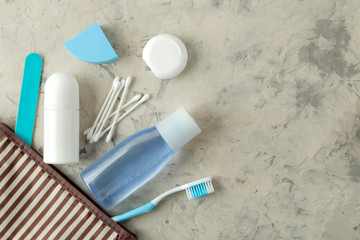 A set of cosmetics and personal care products for travel in a cosmetic bag on a light concrete...