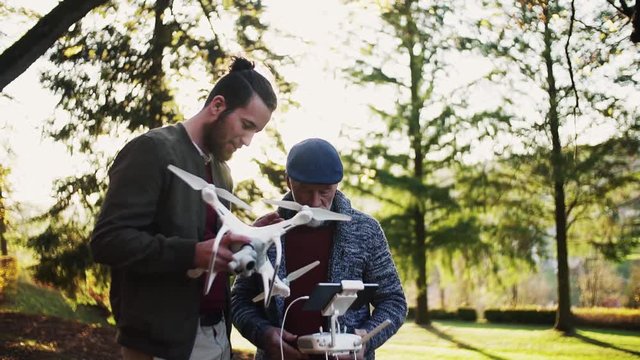 Senior father and his son with drone in nature, talking. Slow motion.
